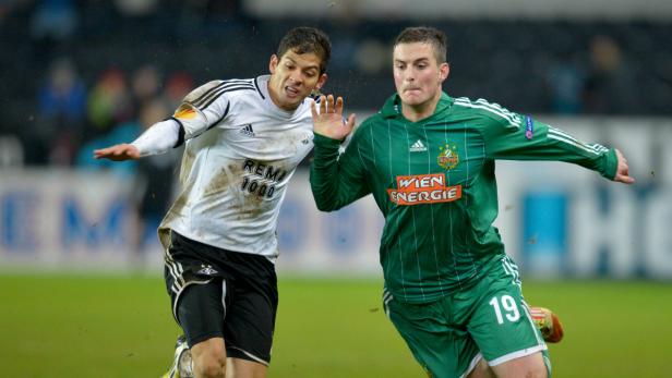 Zwei Fußballspieler kämpfen um den Ball auf dem Spielfeld.