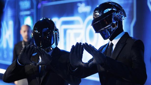 Die Band Daft Punk posiert vor einem „Tron“-Logo.