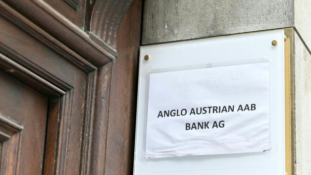 Ein Schild der Anglo Austrian AAB Bank AG hängt neben einer Holztür.
