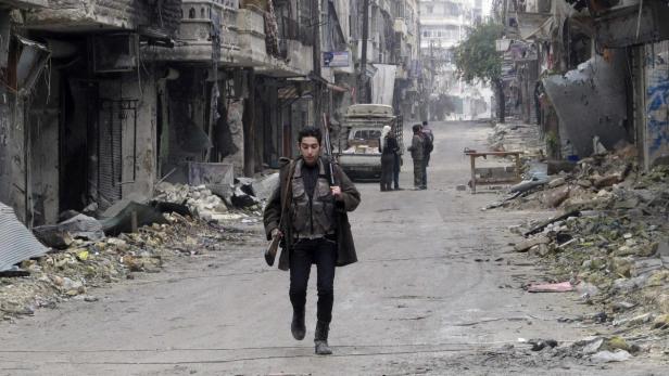 A member of the Free Syrian Army carries weapons while walking down a debris-filled street in Aleppo&#039;s district of Salaheddine February 19, 2013. Picture taken February 19, 2013. REUTERS/Abdalghne Karoof (SYRIA - Tags: CIVIL UNREST MILITARY POLITICS CONFLICT)
