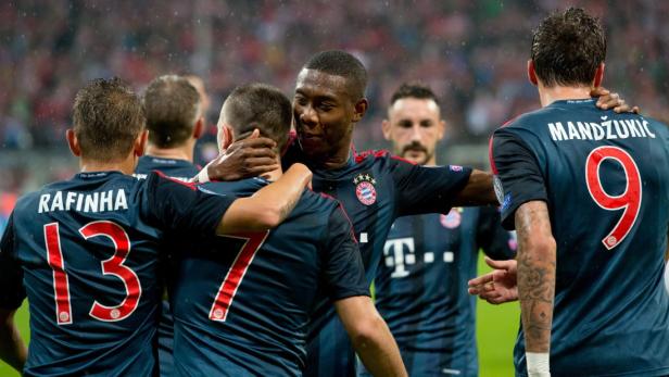 Spieler des FC Bayern München umarmen sich auf dem Spielfeld.