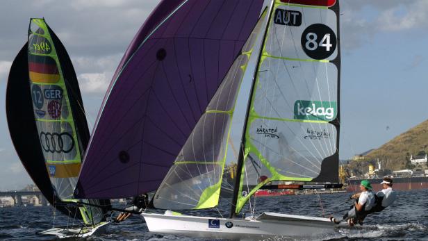 Zwei Segelboote mit den Flaggen Deutschlands und Österreichs auf dem Wasser.
