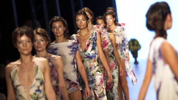 Models präsentieren florale Kleider auf einer Modenschau.