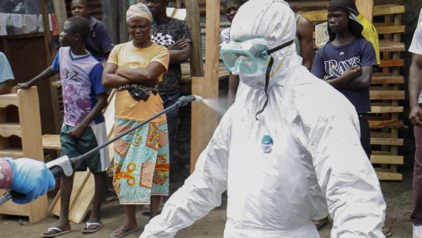 Während seine Kollegen Leichen einsammeln, wird ein Rot-Kreuz-Mitarbeiter in einem Vorort Monrovias, der Hauptstadt Liberias, desinfiziert.
