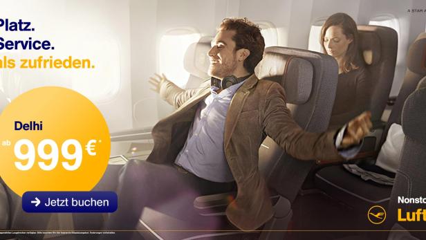 Ein Mann sitzt entspannt in einem Lufthansa-Flugzeug auf dem Weg nach Delhi.