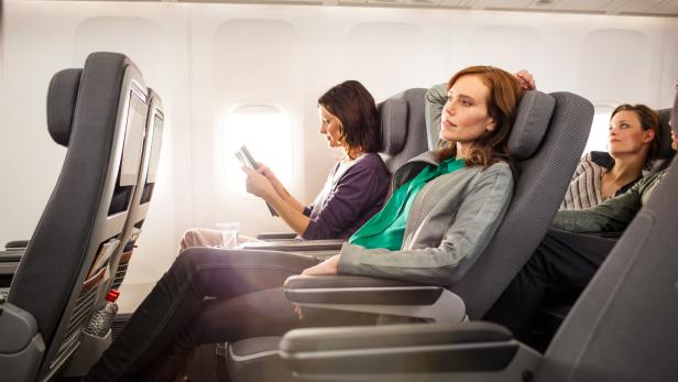 Passagiere sitzen in einem Flugzeug auf ihren Sitzen.