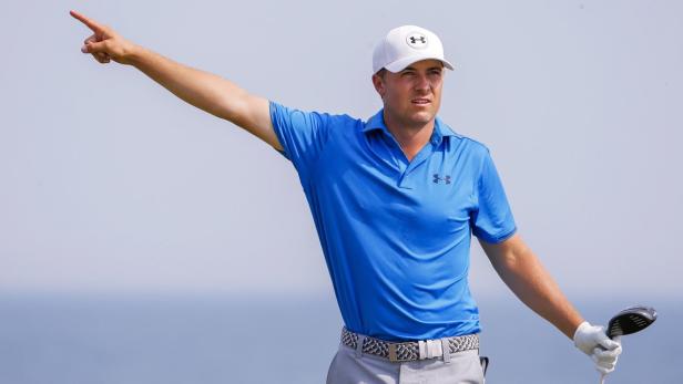 Ein Golfspieler in blauer Kleidung und Kappe zeigt mit dem Finger in die Ferne.