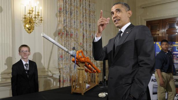 Barack Obama posiert mit zwei Jungen und einer Erfindung aus Rohren.