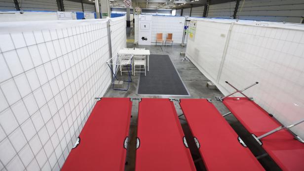 Eine Notunterkunft mit Feldbetten und abgetrennten Bereichen.