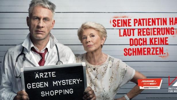 Ein Arzt und eine ältere Dame stehen vor einer Wand mit Größenmarkierungen; der Arzt hält ein Schild mit der Aufschrift „Ärzte gegen Mystery-Shopping“.