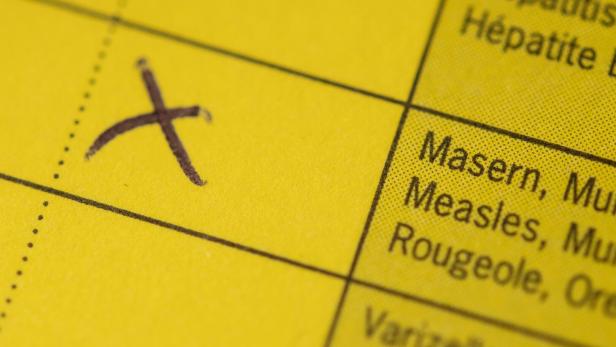 Symbolbild: Ein aufgeschlagener Impfpass mit einem Kreuz im Masernfeld