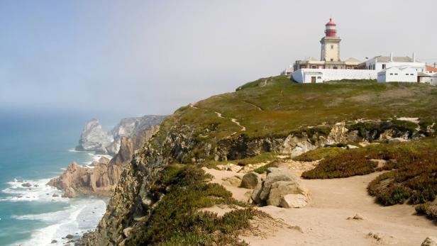 Ein Leuchtturm steht auf einer Klippe mit Blick auf das Meer.