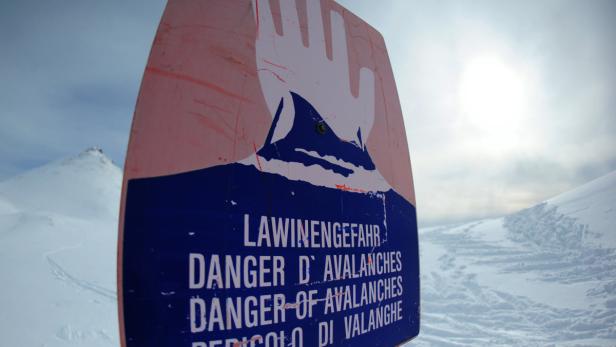 Ein Schild warnt vor Lawinengefahr in den Bergen.