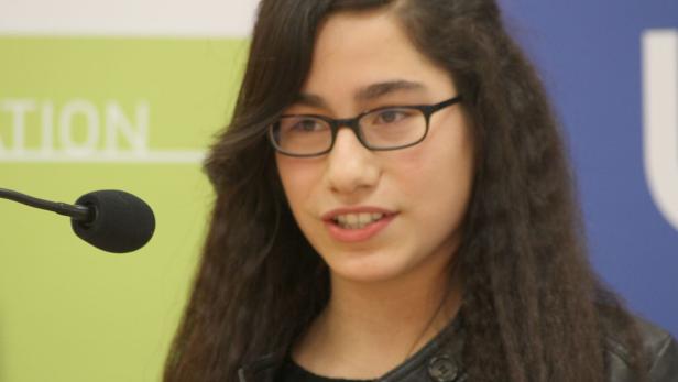 Eine junge Frau mit Brille spricht vor einem Mikrofon.