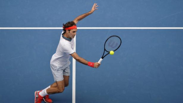 Roger Federer schlägt einen Tennisball auf einem blauen Platz.