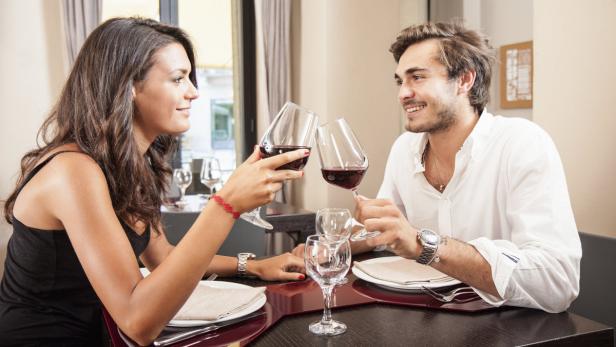 Ein Paar stößt in einem Restaurant mit Rotwein an.
