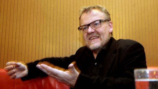 Ein Mann mit Brille gestikuliert während eines Gesprächs.