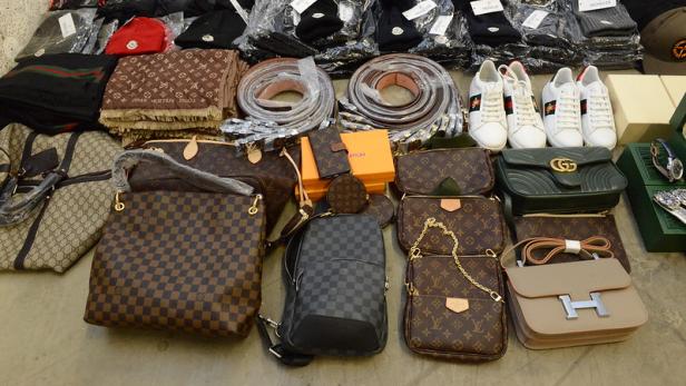 Beschlagnahmte gefälschte Markenartikel wie Handtaschen, Gürtel, Schuhe und Mützen.