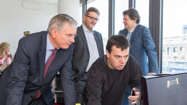 Eine Gruppe von vier Personen, darunter ein Mann mit Behinderung, schaut auf einen Computerbildschirm.