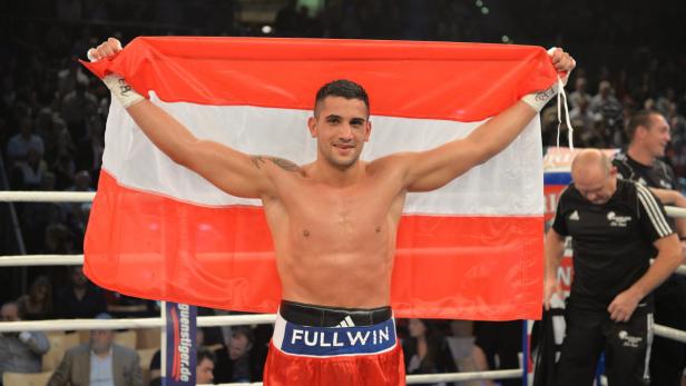 Ein Boxer hält eine österreichische Flagge hoch.