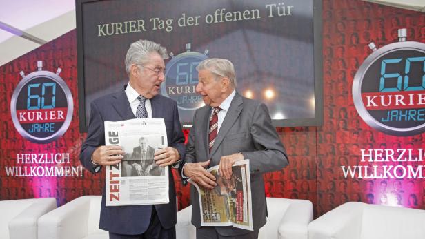 Zwei Männer im Anzug halten Zeitungen vor dem Hintergrund des „Kurier Tag der offenen Tür“.