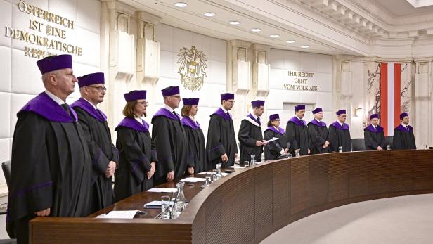 Eine Gruppe von Richtern in Roben steht in einem Gerichtssaal in Österreich.