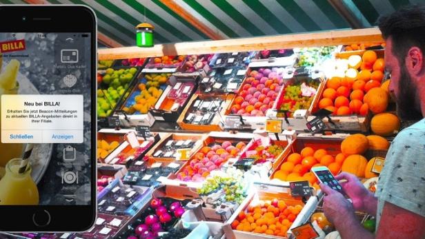Ein Mann benutzt die Billa-App in einem Supermarkt vor einem Obstregal.