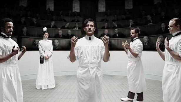 Szene aus „The Knick“ mit Clive Owen und anderen Schauspielern in weißen Arztkitteln in einem Hörsaal.