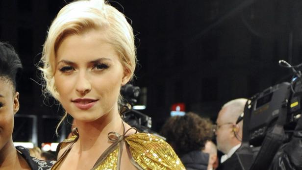 Porträt einer blonden Frau mit goldenem Kleid auf einer Veranstaltung.