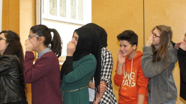 Eine Gruppe von Jugendlichen flüstert sich gegenseitig etwas ins Ohr.