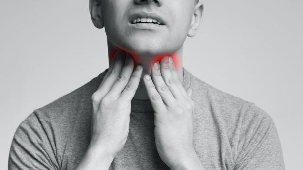 Man with thyroid gland problem, touching his neck