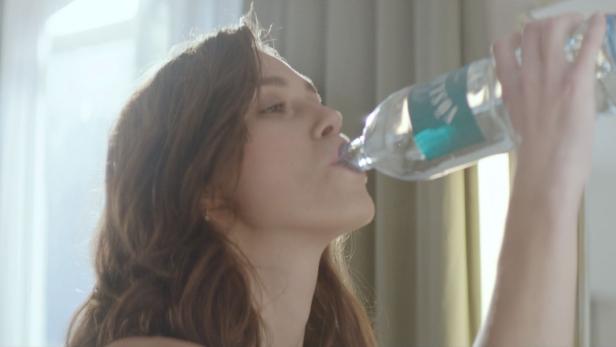 Eine Frau trinkt Wasser aus einer Plastikflasche.