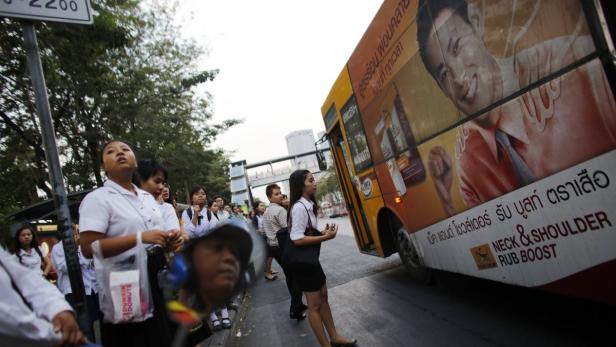 Eine Gruppe von Menschen wartet an einer Bushaltestelle in Thailand.