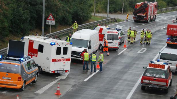 Auf einer Autobahn stehen Einsatzfahrzeuge von Feuerwehr, Notarzt und Polizei nach einem Unfall.