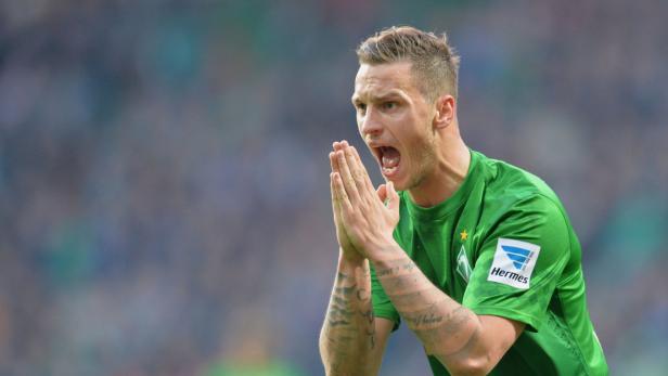 Ein Fußballspieler in Grün schreit mit erhobenen Händen.