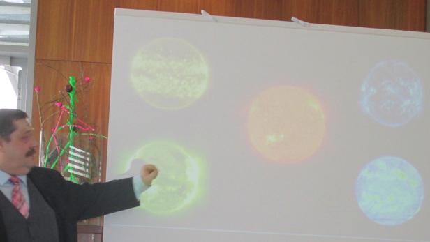 Ein Mann präsentiert eine Projektion von verschiedenen Darstellungen der Sonne.