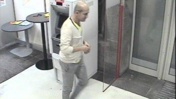 Ein Mann steht in der Nähe eines Geldautomaten.