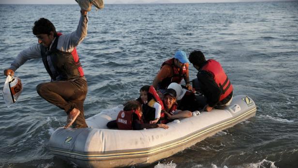Eine Gruppe von Menschen, darunter Kinder, sitzt in einem Schlauchboot auf dem Meer.