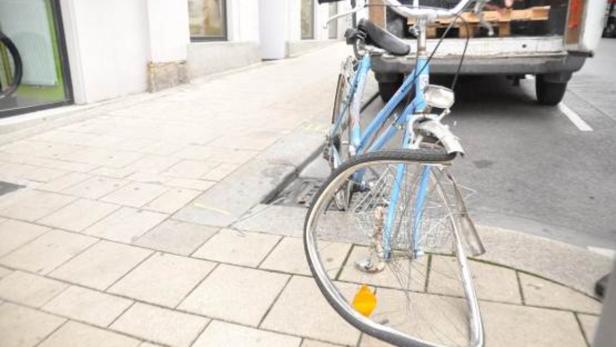 Ein blaues Fahrrad mit verbogenem Vorderrad steht am Straßenrand.