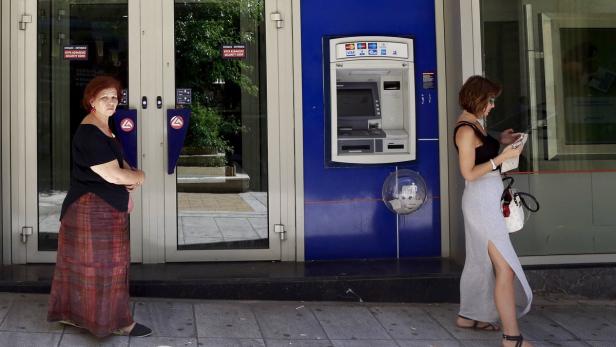 Zwei Frauen vor einer Bankfiliale mit einem Geldautomaten.