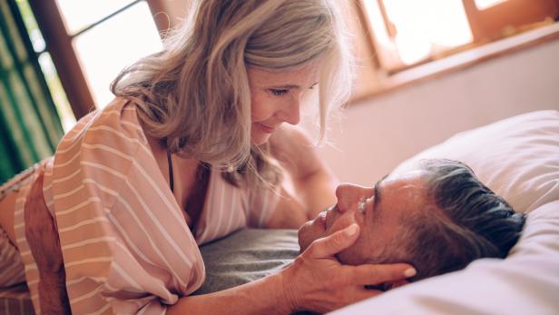 Passionate mature couple flirting while lying down in bed