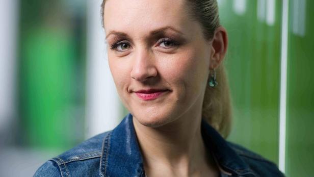Porträt einer lächelnden Frau mit blonden Haaren und Jeansjacke.