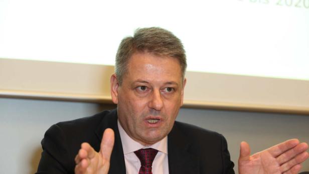 Ein Mann in Anzug gestikuliert während einer Präsentation.