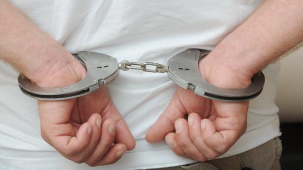 Ein Mann mit Handschellen auf dem Rücken.