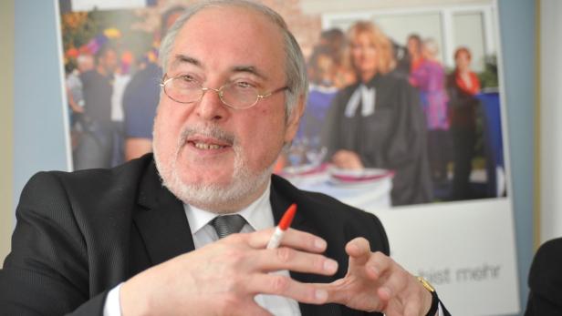Ein Mann mit Brille und Bart gestikuliert mit einem Stift in der Hand.