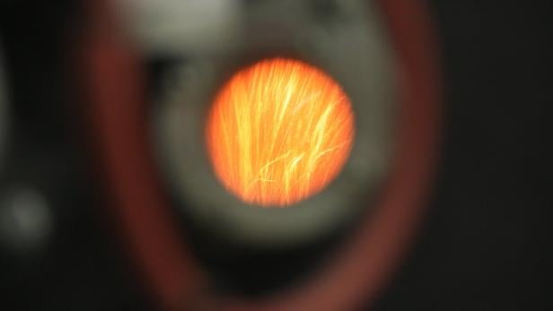 Ein orangefarbener Lichtschein mit feinen Linien in einem dunklen Umfeld.