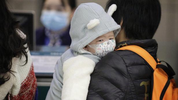Ein Kind trägt am Flughafen Guangzhou in der chinesischen Provinz Guangdong eine Atemmaske.