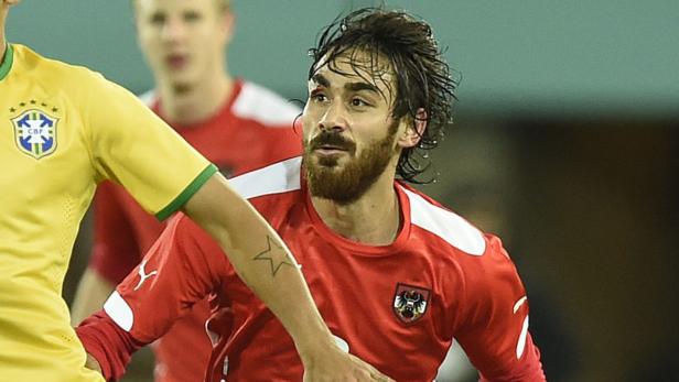 Ein österreichischer Fußballspieler mit Bart und Stirnwunde auf dem Spielfeld.