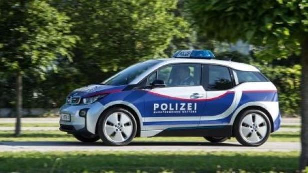 Ein blau-weißes Polizeiauto fährt auf einer Straße.