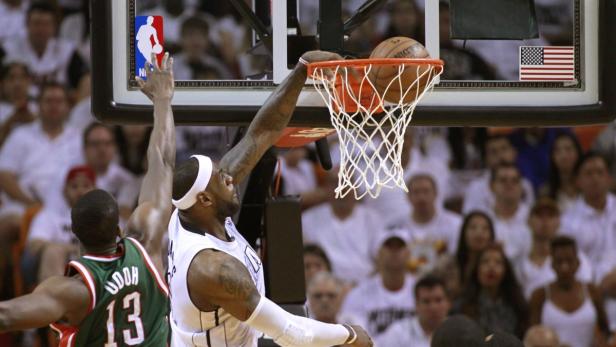 Miami Heat forward LeBron James (C) scores past Milwaukee Bucks forward Ekpe Udoh (L) and Luc Richard Mbah a Moute (R) in the second half during their NBA first round Game 1 playoff basketball game in Miami, Florida April 21, 2013. REUTERS/Joe Skipper (UNITED STATES - Tags: SPORT BASKETBALL)